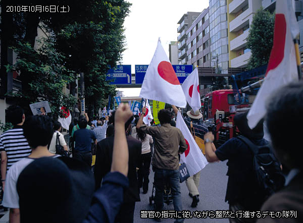 警官の指示に従いながら整然と行進するデモの隊列